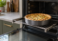 Torta salata in una teglia metallica su una griglia estraibile davanti a un forno elettrico aperto